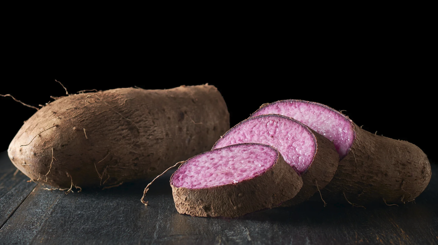 Tubercule d’ube entier et tranches violettes naturelles sur fond noir